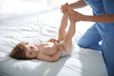 Orthopedist examining cute little baby on bed