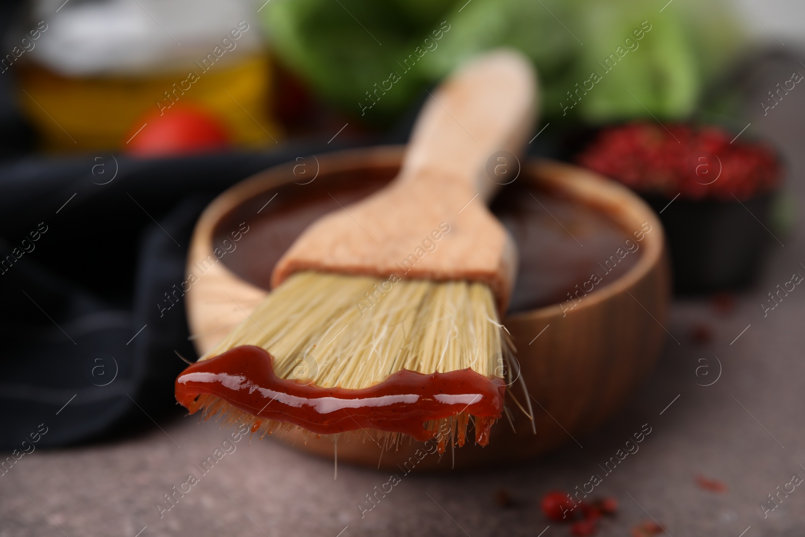 Photo of Marinade in bowl and basting brush on brown table, selective focus