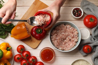 Photo of Woman making stuffed peppers with ground meat at white wooden table, top view