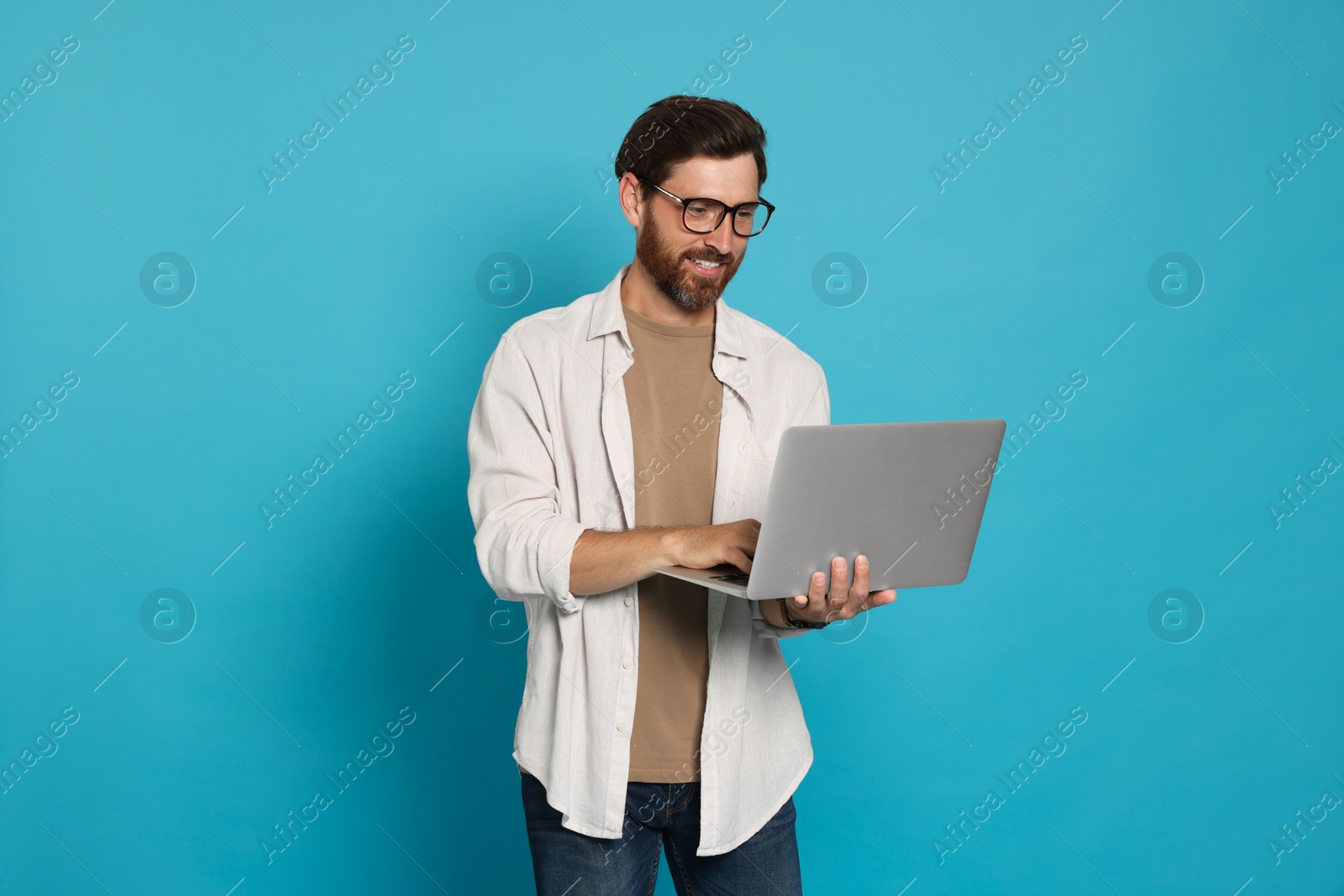 Photo of Handsome man with laptop on light blue background