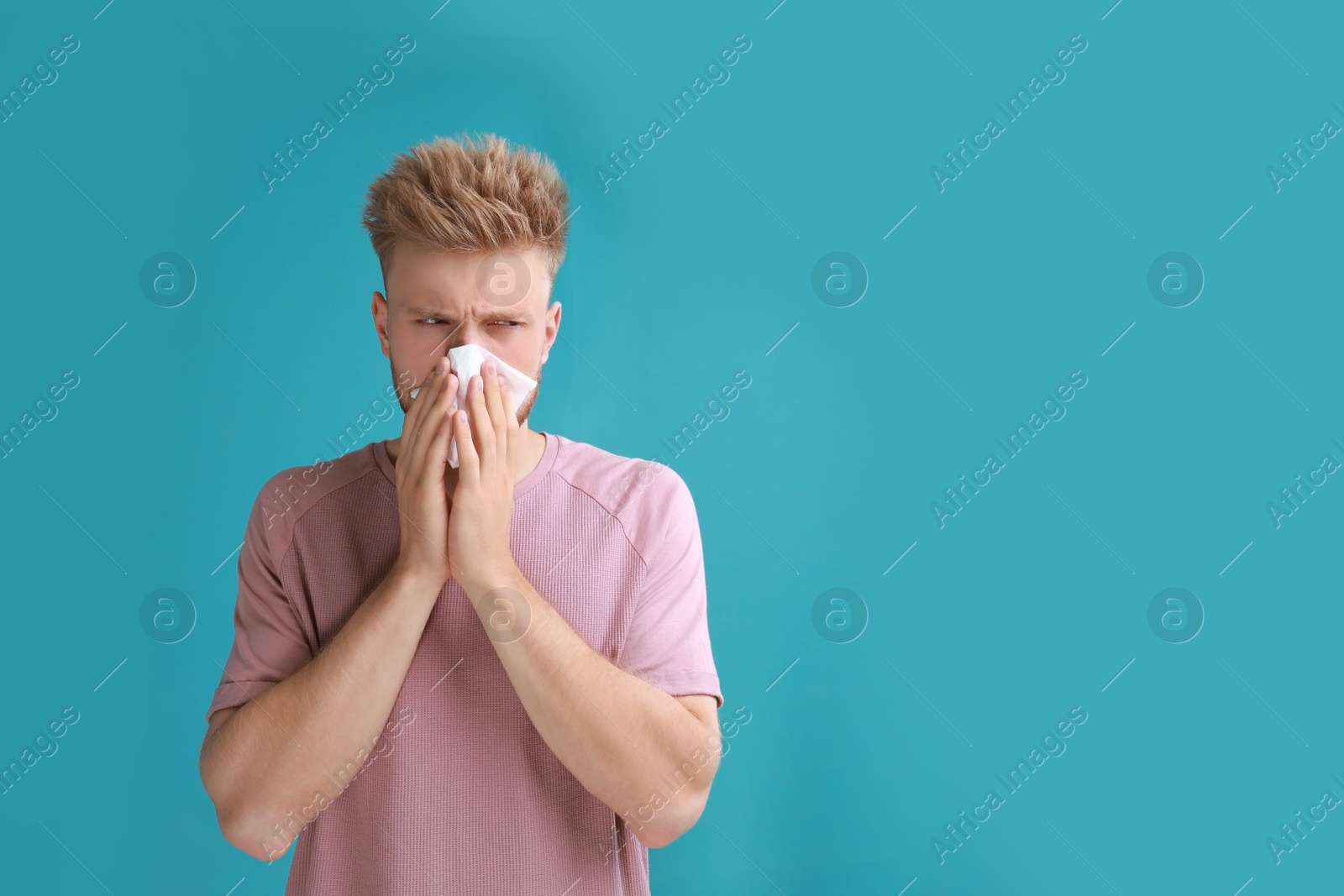 Photo of Young man suffering from allergy on blue background. Space for text