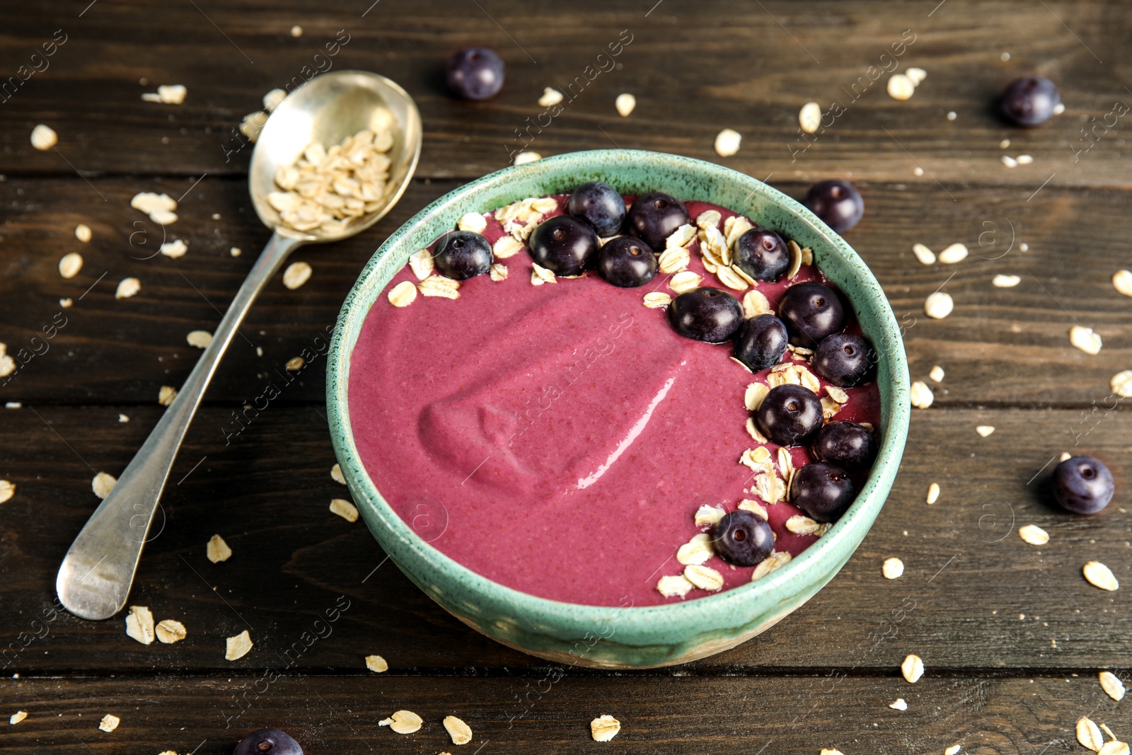 Photo of Bowl with tasty acai smoothie on wooden table