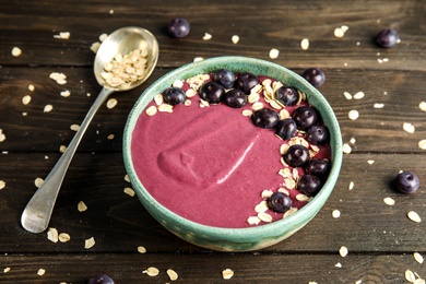 Photo of Bowl with tasty acai smoothie on wooden table