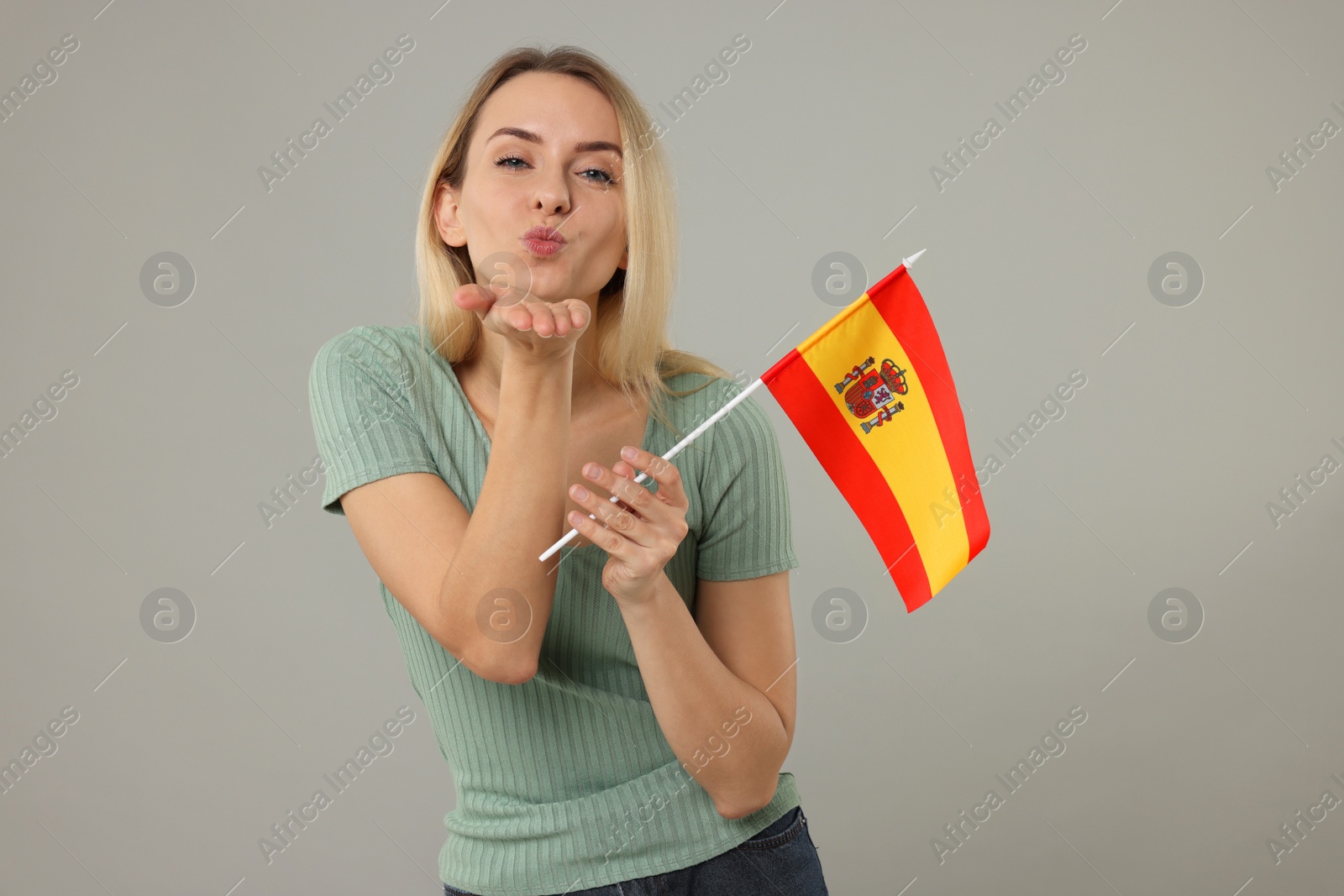 Photo of Woman with flag of Spain blowing kiss on grey background