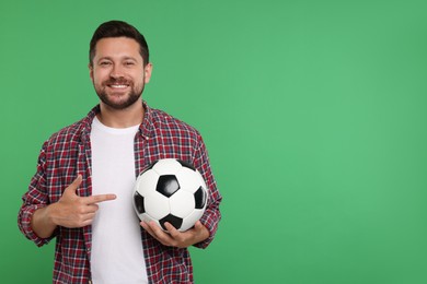 Photo of Happy sports fan with ball on green background. Space for text