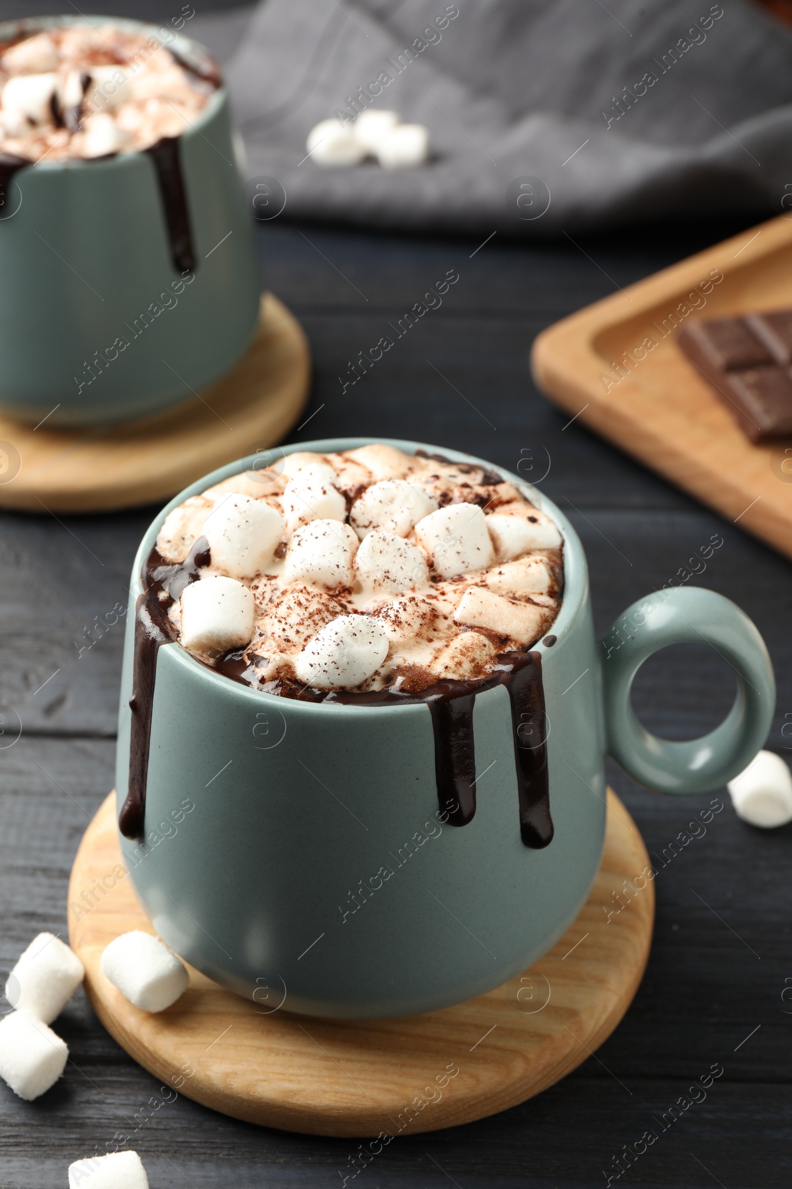 Photo of Cups of aromatic hot chocolate with marshmallows and cocoa powder on dark gray wooden table, closeup