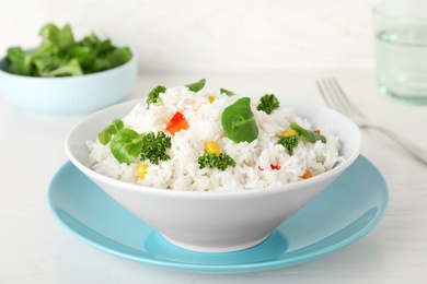 Plate of boiled rice with vegetables on table