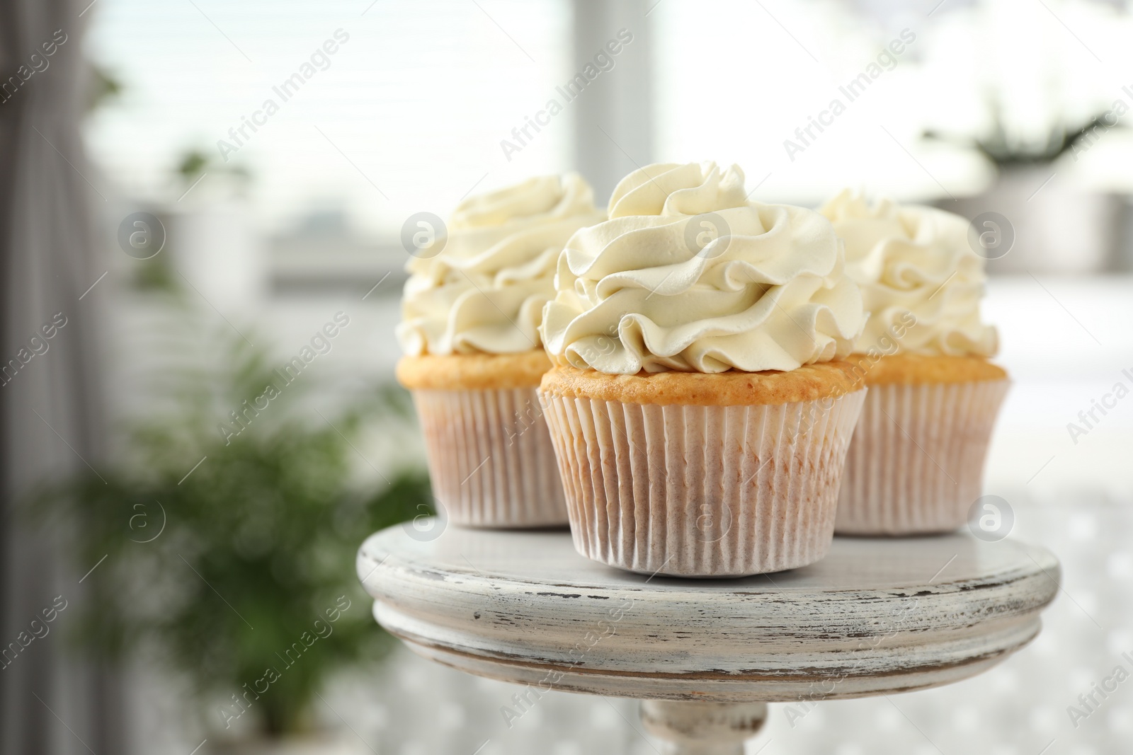 Photo of Tasty cupcakes with vanilla cream on stand, closeup. Space for text