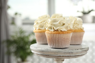 Tasty cupcakes with vanilla cream on stand, closeup. Space for text