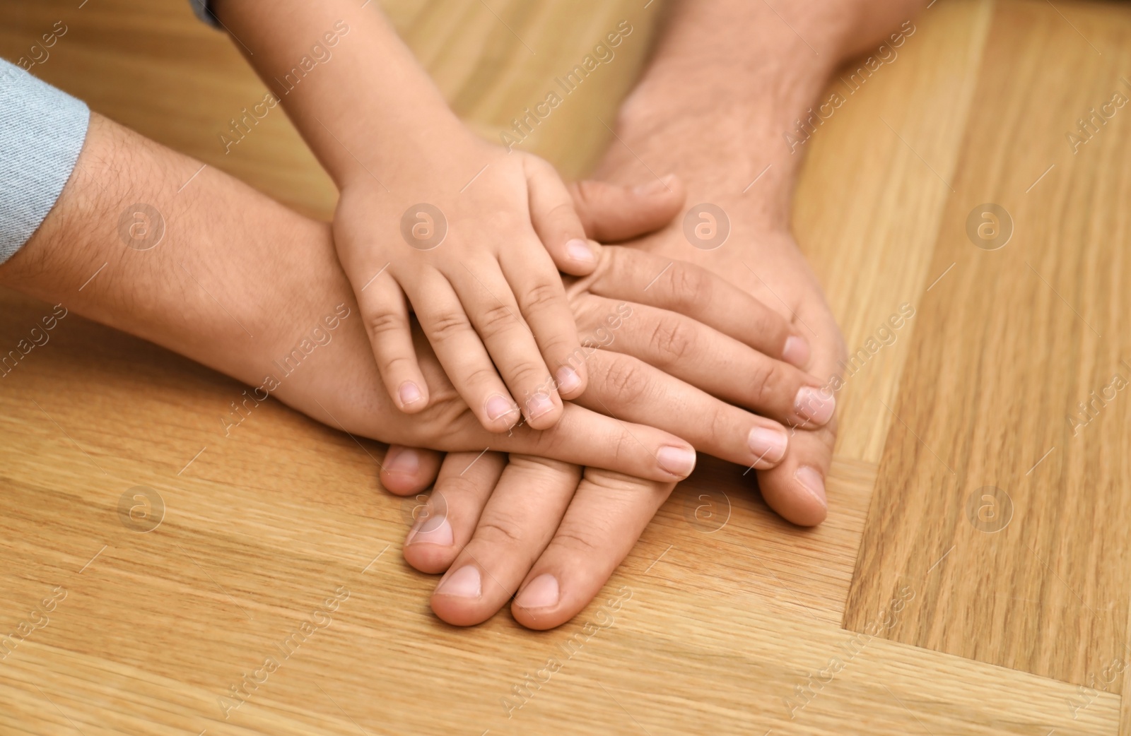 Photo of Happy family holding hands on wooden background, closeup