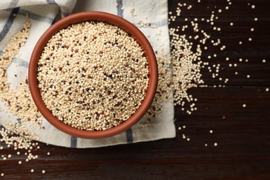 Photo of Bowl with raw quinoa seeds on wooden table, top view. Space for text