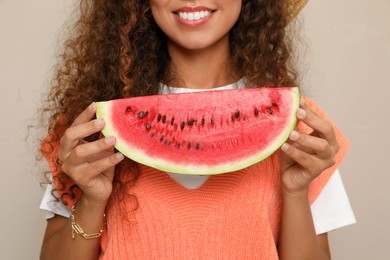 Photo of Beautiful young African American woman with slice of watermelon on beige background, closeup