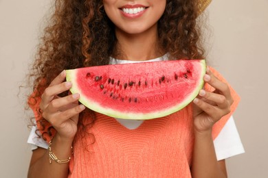 Beautiful young African American woman with slice of watermelon on beige background, closeup