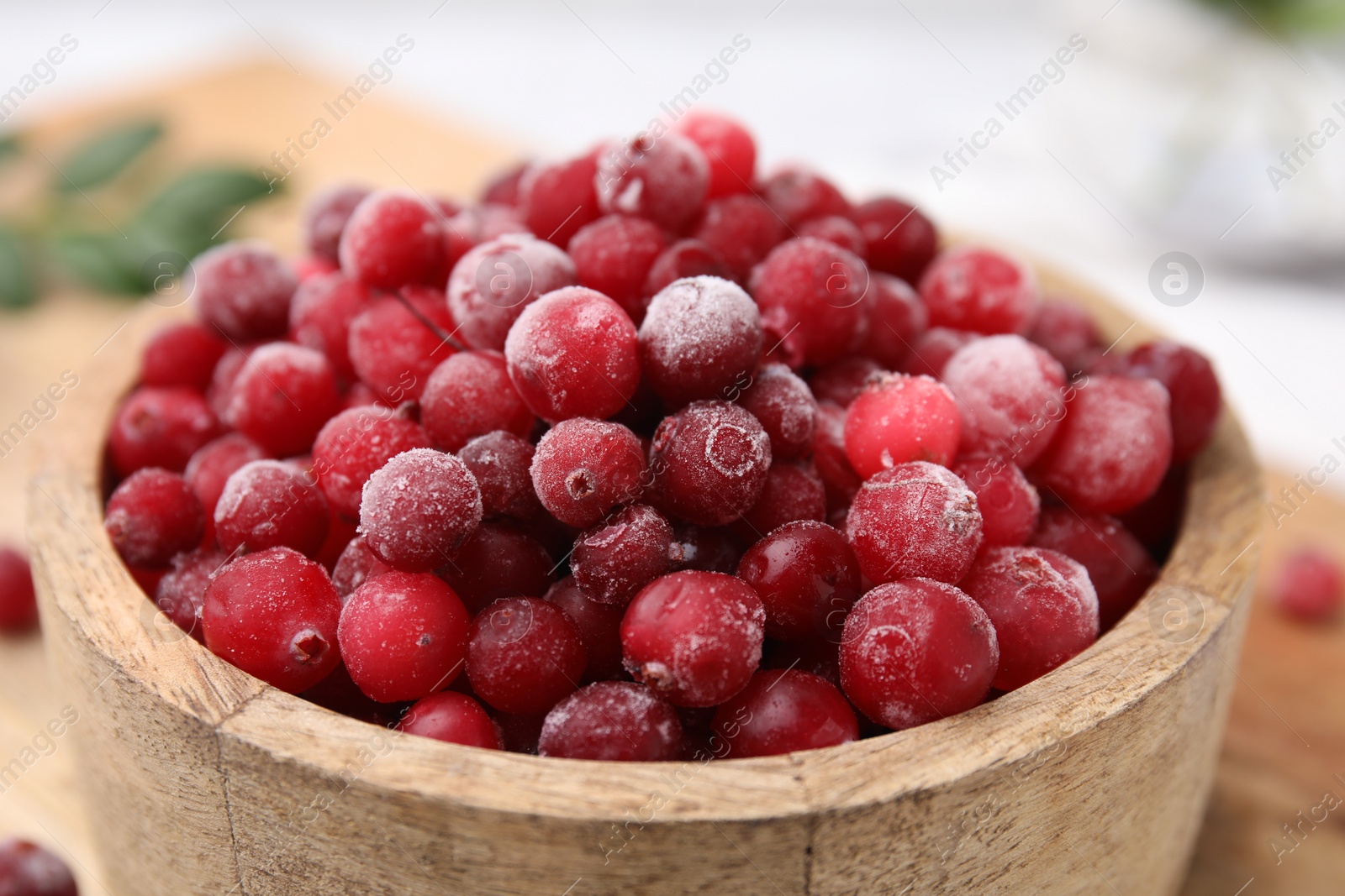 Photo of Frozen red cranberries in bowl on table, closeup