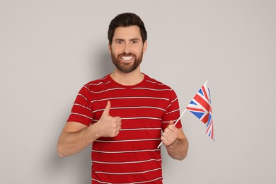 Photo of Man with flag of United Kingdom showing thumb up on light grey background