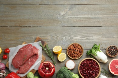 Flat lay composition with fresh meat and other products on wooden table, space for text. Balanced diet