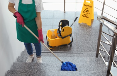 Photo of Young woman with mop cleaning stairs