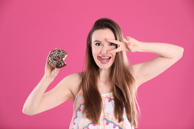 Beautiful young woman with donut on pink background