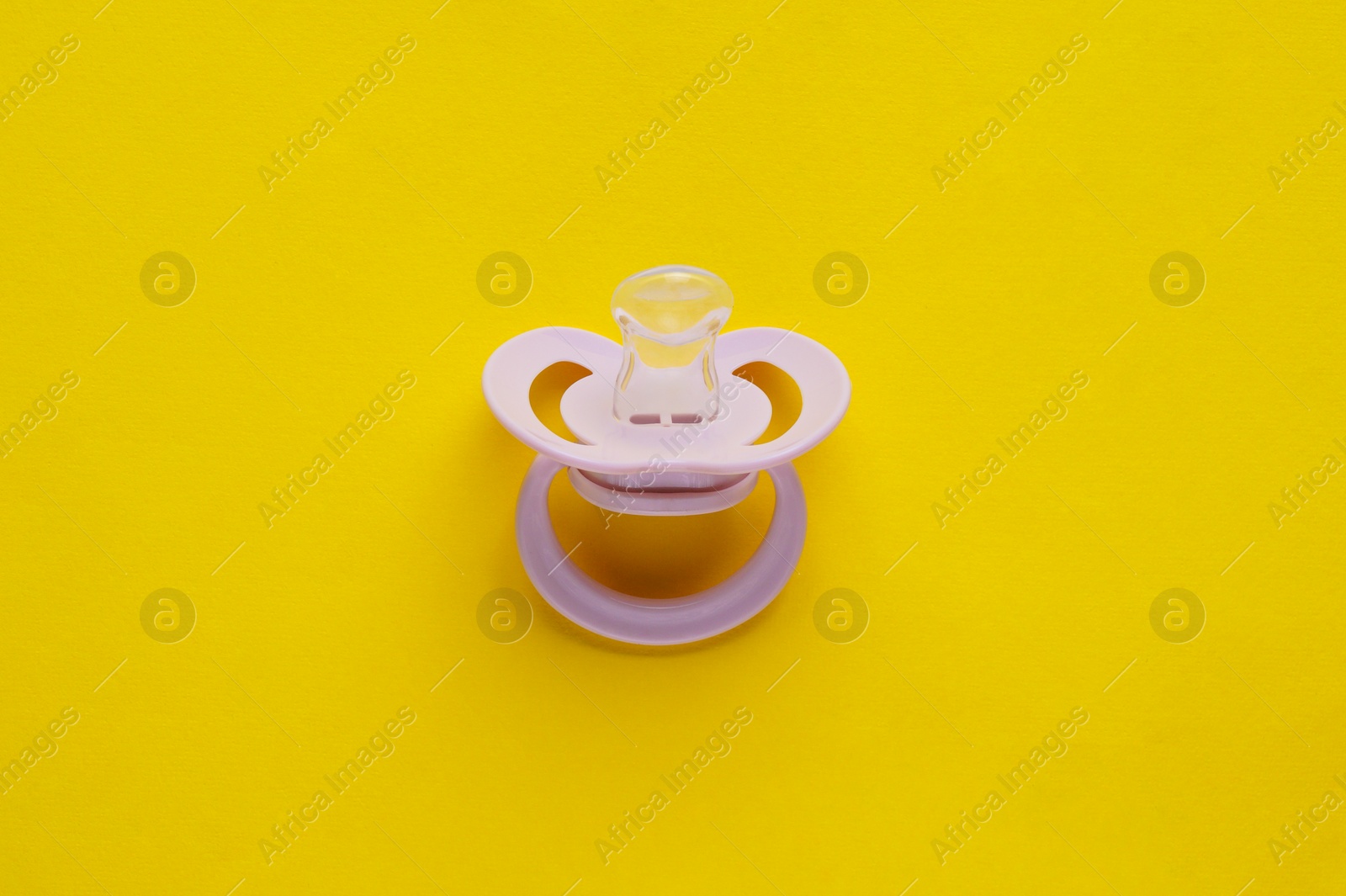 Photo of New baby pacifier on yellow background, top view