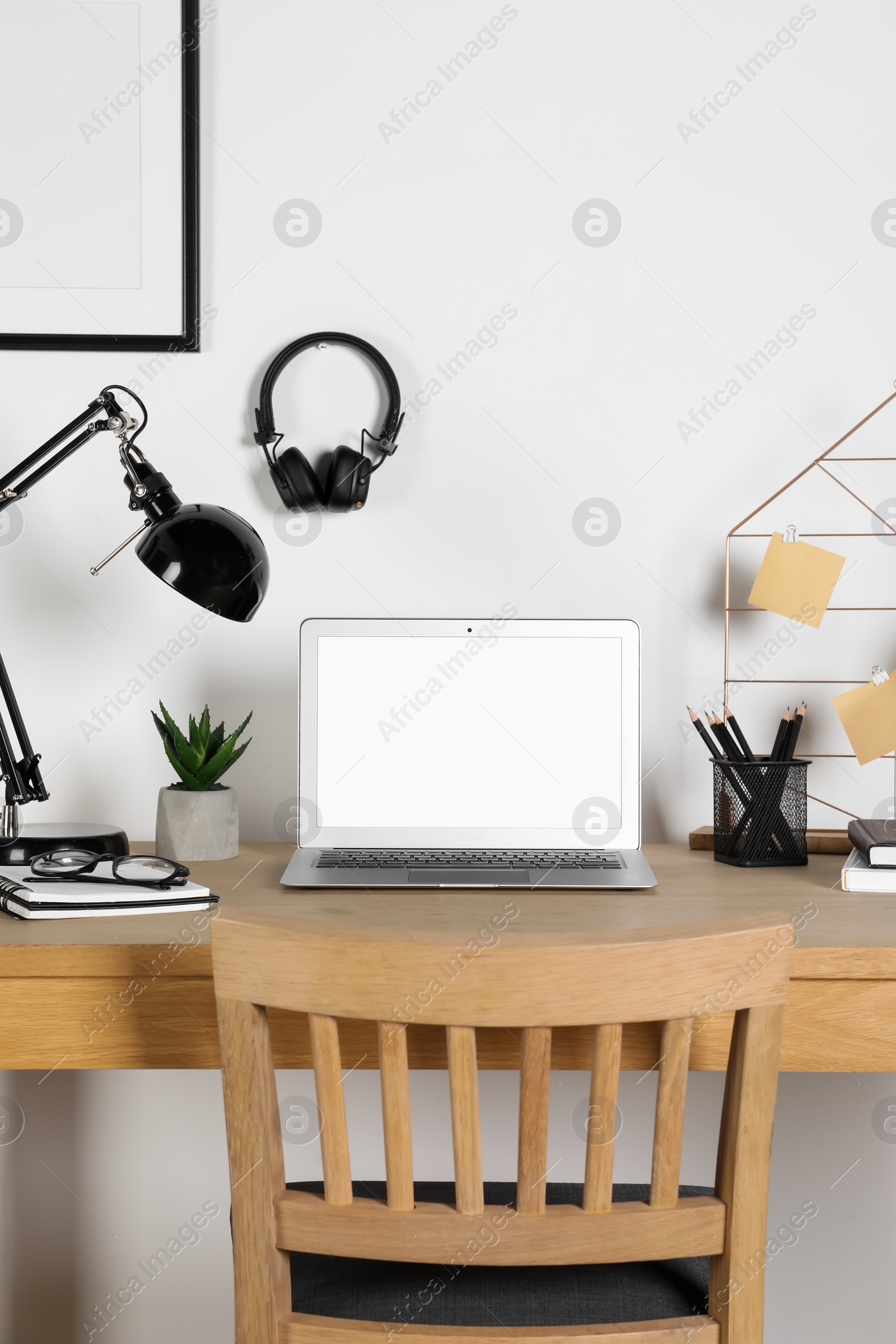 Photo of Home workplace. Laptop, lamp and stationery on wooden desk