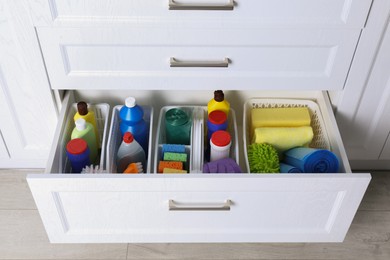 Photo of Different cleaning supplies in open drawer indoors