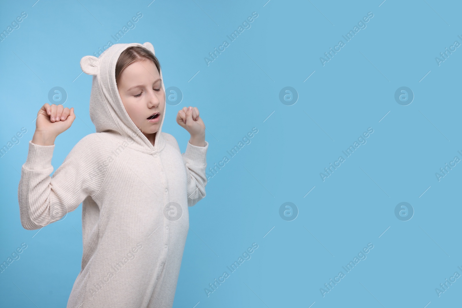 Photo of Sleepy girl yawning on light blue background, space for text. Insomnia problem
