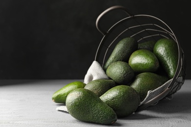 Photo of Delicious ripe avocados on grey wooden table against dark background