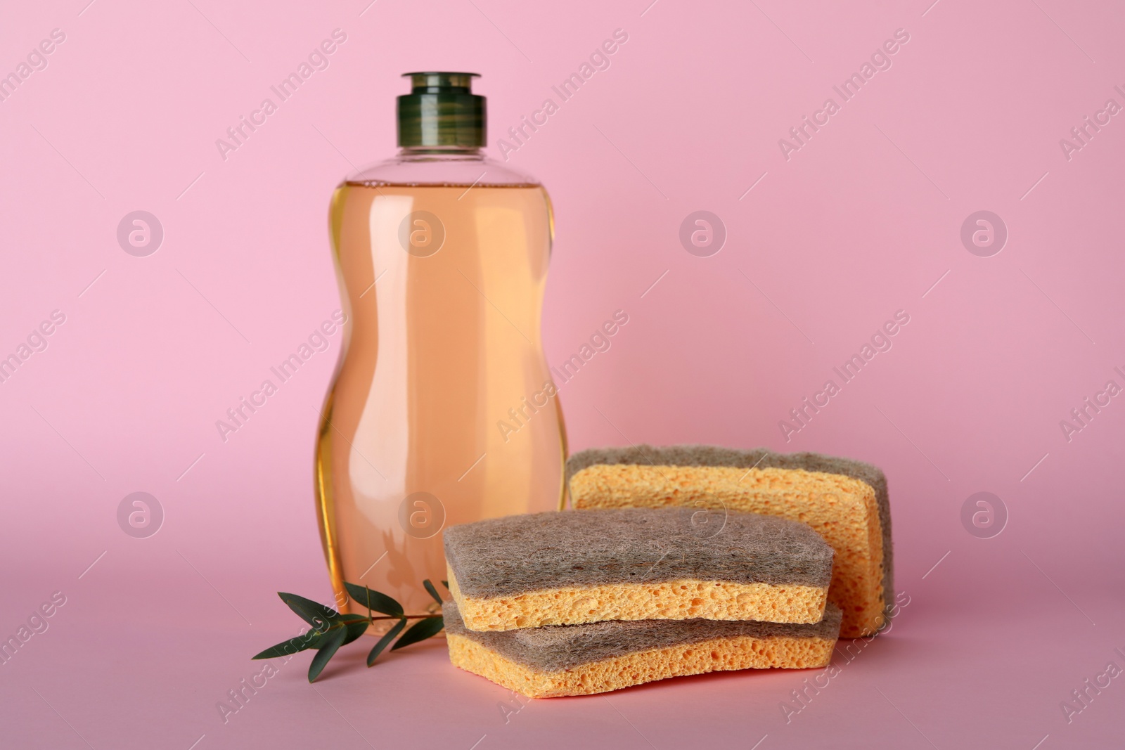Photo of Cleaning detergent and sponges on pink background