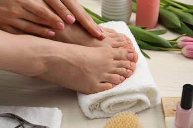 Photo of Woman with neat toenails after pedicure procedure on white wooden floor, closeup