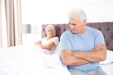 Photo of Mature couple with relationship problems ignoring each other in bedroom