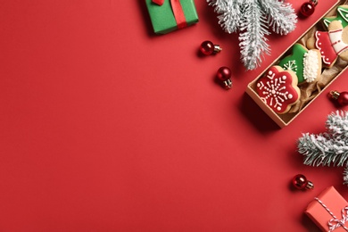 Photo of Flat lay composition with tasty homemade cookies and Christmas decorations on red background. Space for text