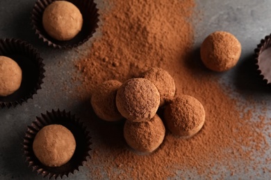 Photo of Tasty chocolate truffles powdered with cocoa on grey background, top view