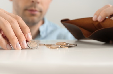 Photo of Man putting coins in wallet at table, closeup