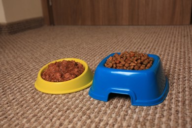 Photo of Dry and wet pet food in feeding bowls on soft carpet