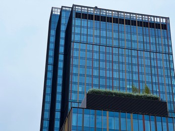 Photo of Modern multistory building with garden on roof near skyscrapers