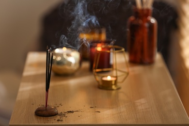 Incense sticks smoldering on wooden table in room. Space for text