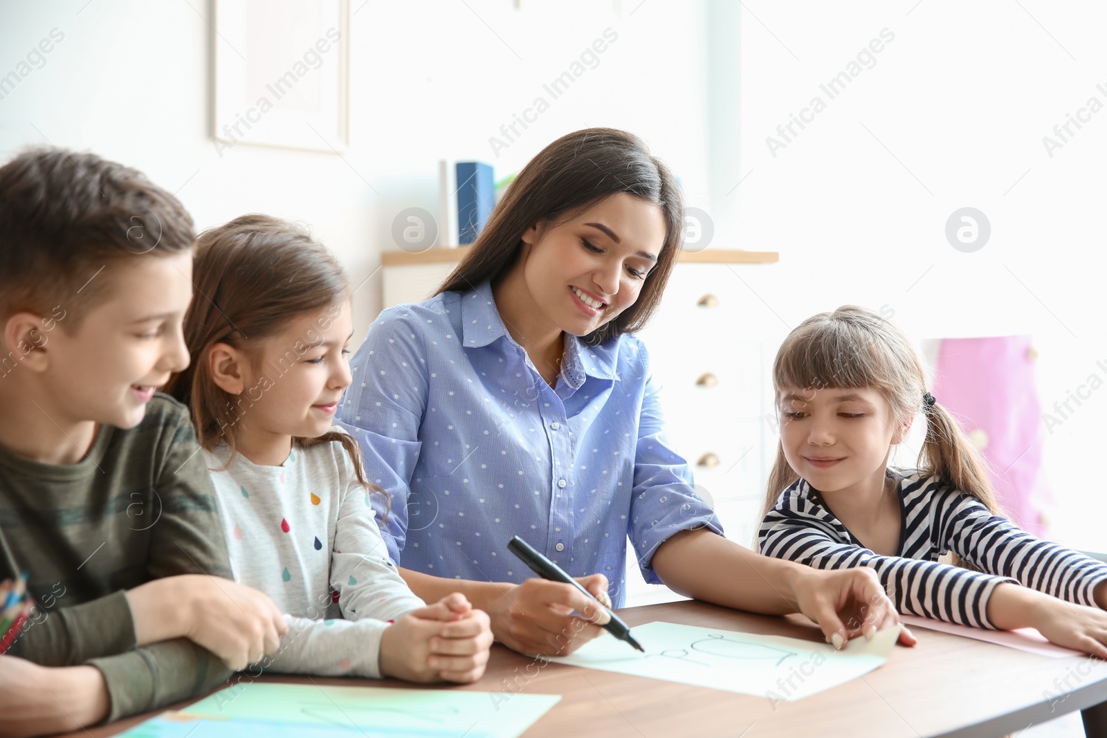 Photo of Cute little children with teacher in classroom at school