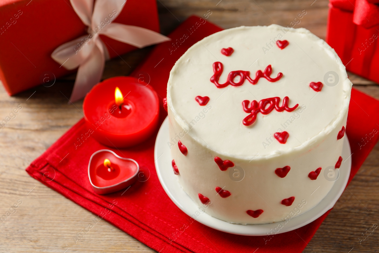 Photo of Bento cake with text Love You, candles and gift boxes on wooden table. St. Valentine's day surprise