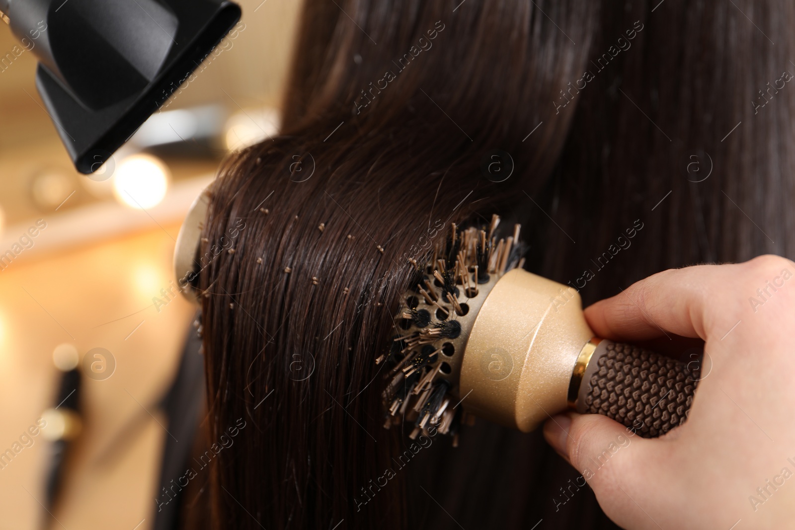 Photo of Hairdresser blow drying client's hair in salon, closeup