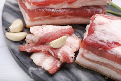 Pieces of tasty pork fatback with garlic and peppercorns on board, closeup