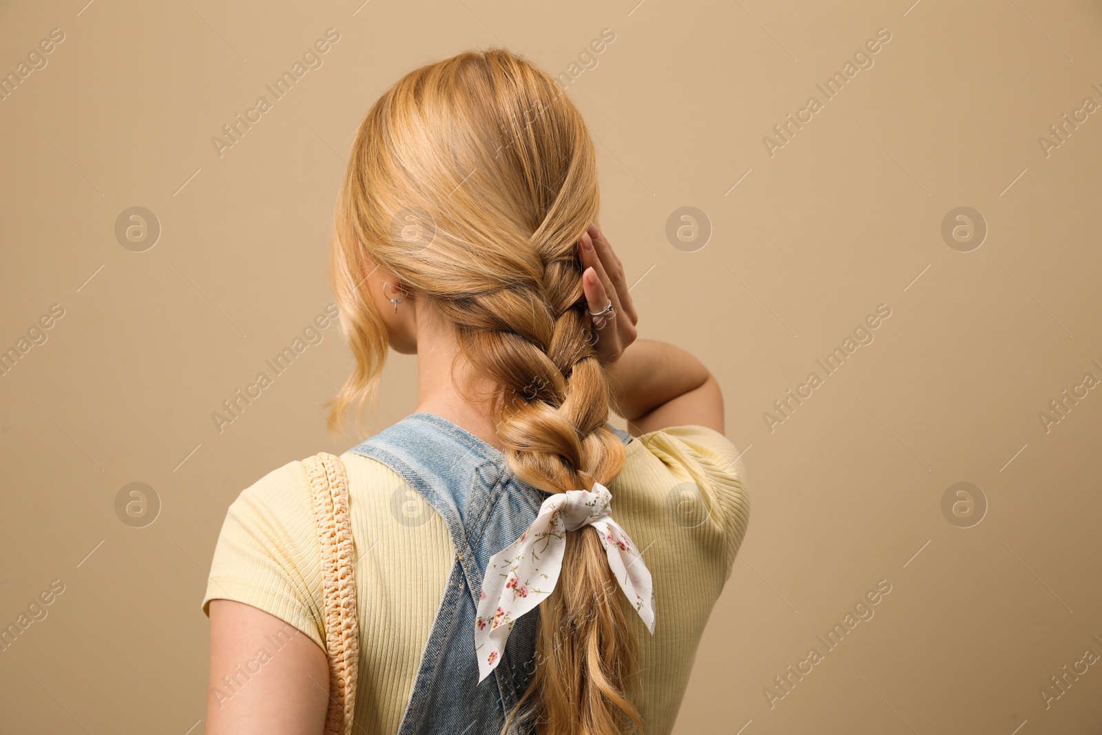 Photo of Young woman with stylish bandana on beige background, back view