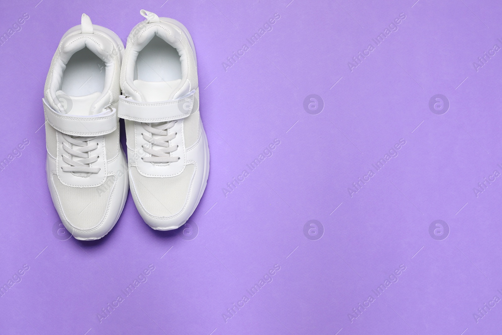 Photo of Pair of comfortable sports shoes on violet background, flat lay. Space for text
