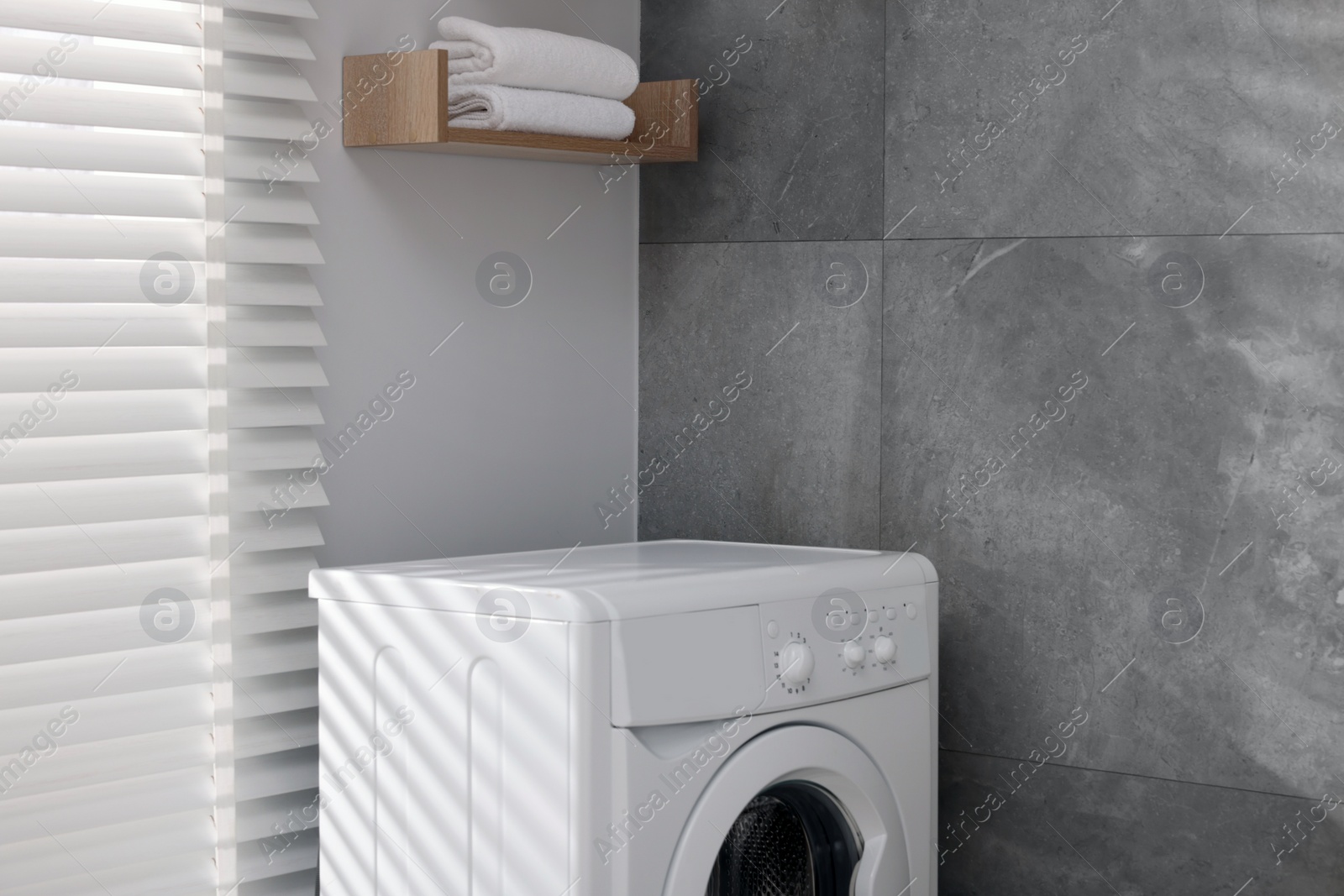 Photo of Laundry room interior with washing machine near grey wall