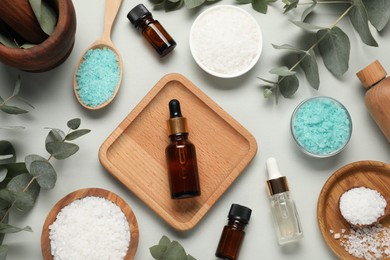 Aromatherapy products. Bottles of essential oil, sea salt and eucalyptus leaves on grey background, flat lay