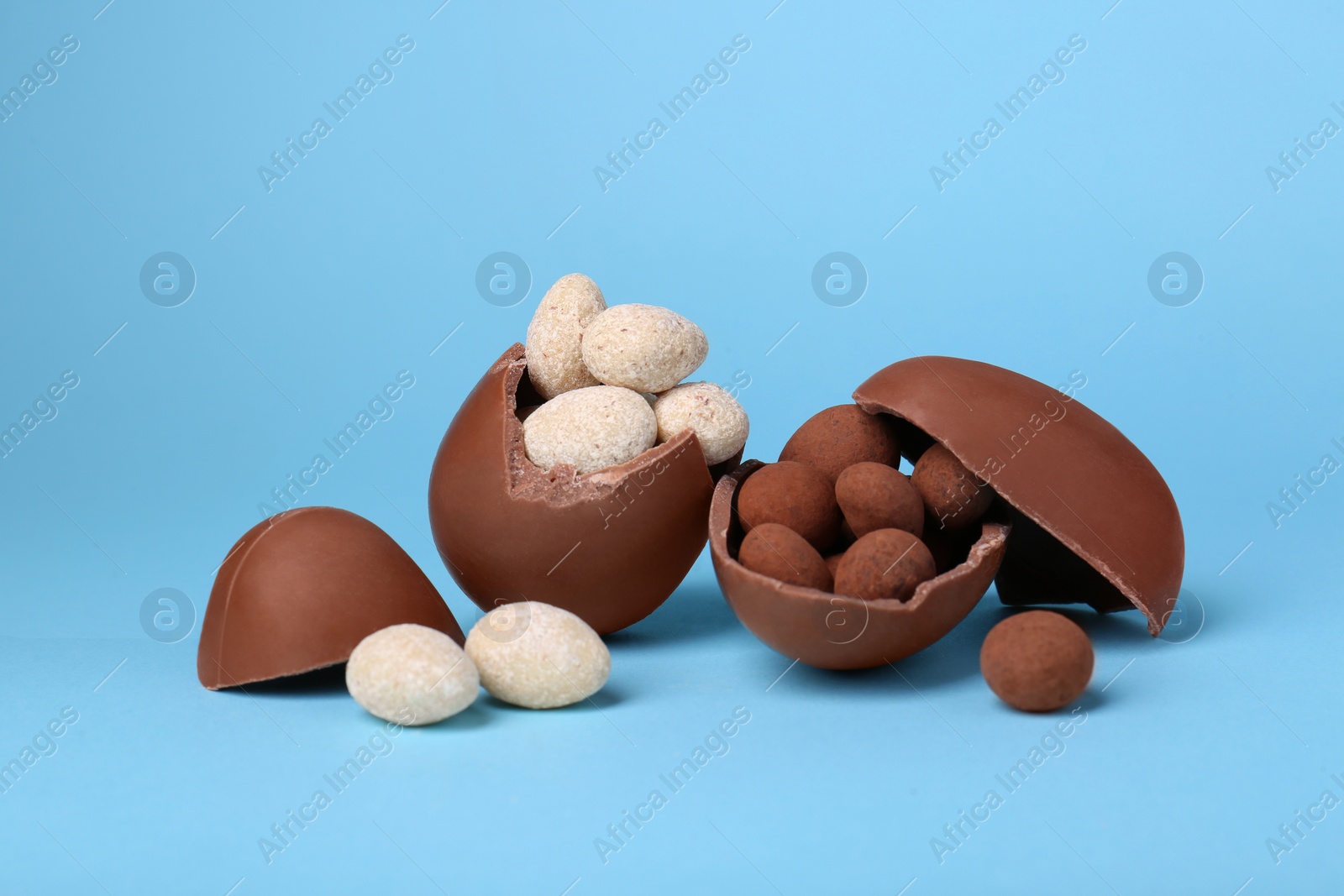 Photo of Tasty broken chocolate eggs and sweets on light blue background