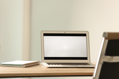 Modern laptop and notebook on table in office