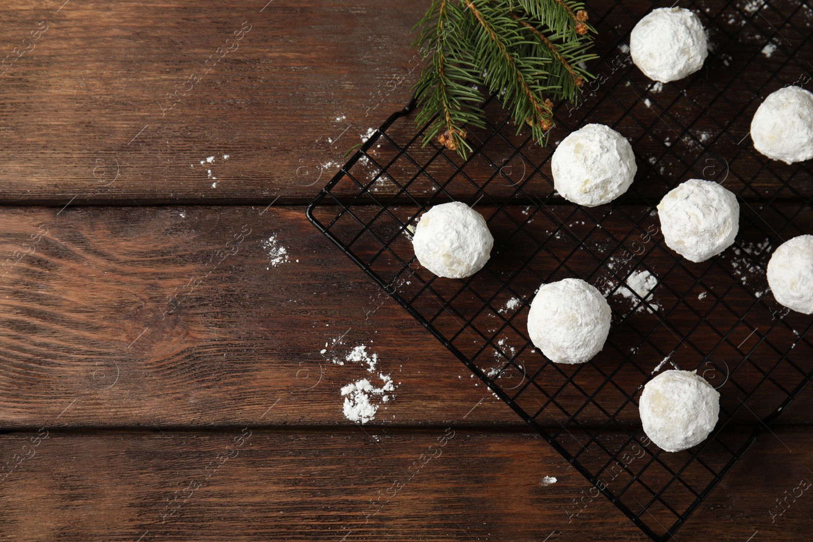 Photo of Christmas snowball cookies and fir tree branches on wooden table, flat lay. Space for text