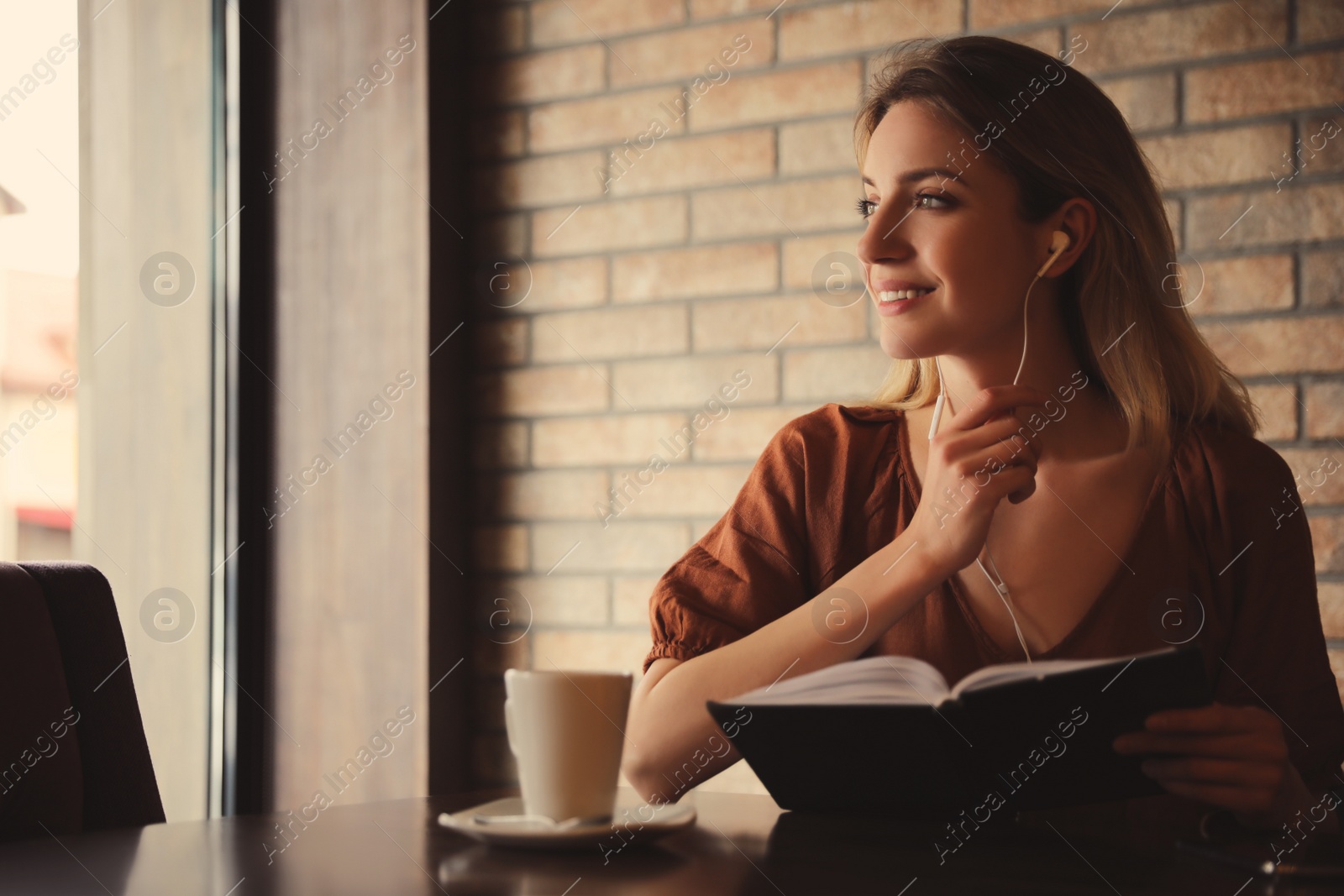 Photo of Woman listening to audiobook at table in cafe