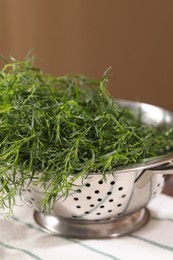 Colander with fresh tarragon leaves on table, closeup