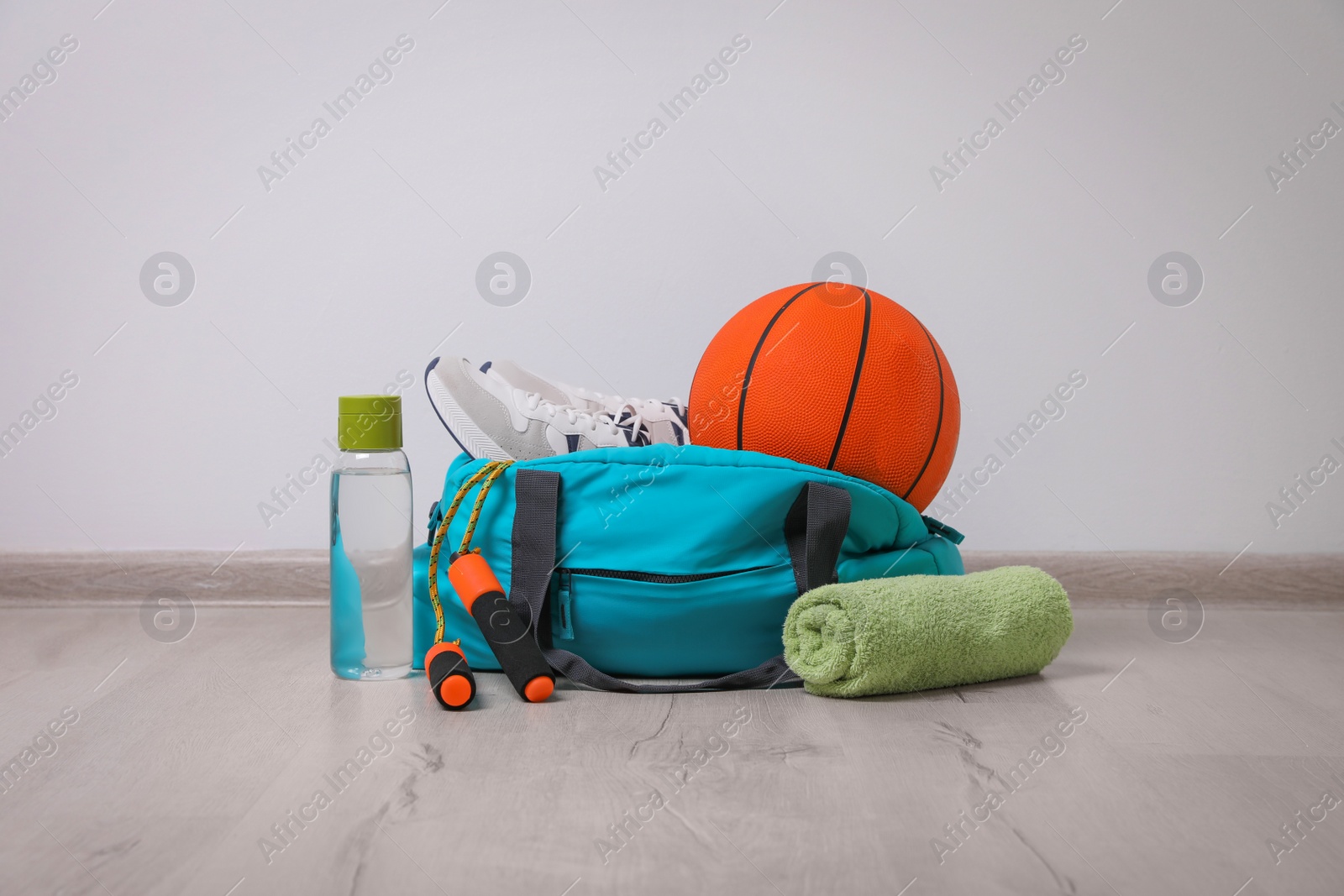 Photo of Bag with different sports equipment on wooden floor indoors